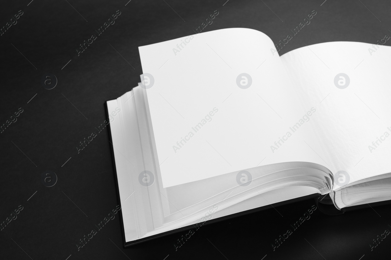 Photo of One open photo album on black background, closeup. Space for text