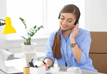 Young woman talking on phone through headset at workplace