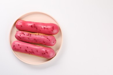 Delicious eclairs covered with glaze on white background, top view