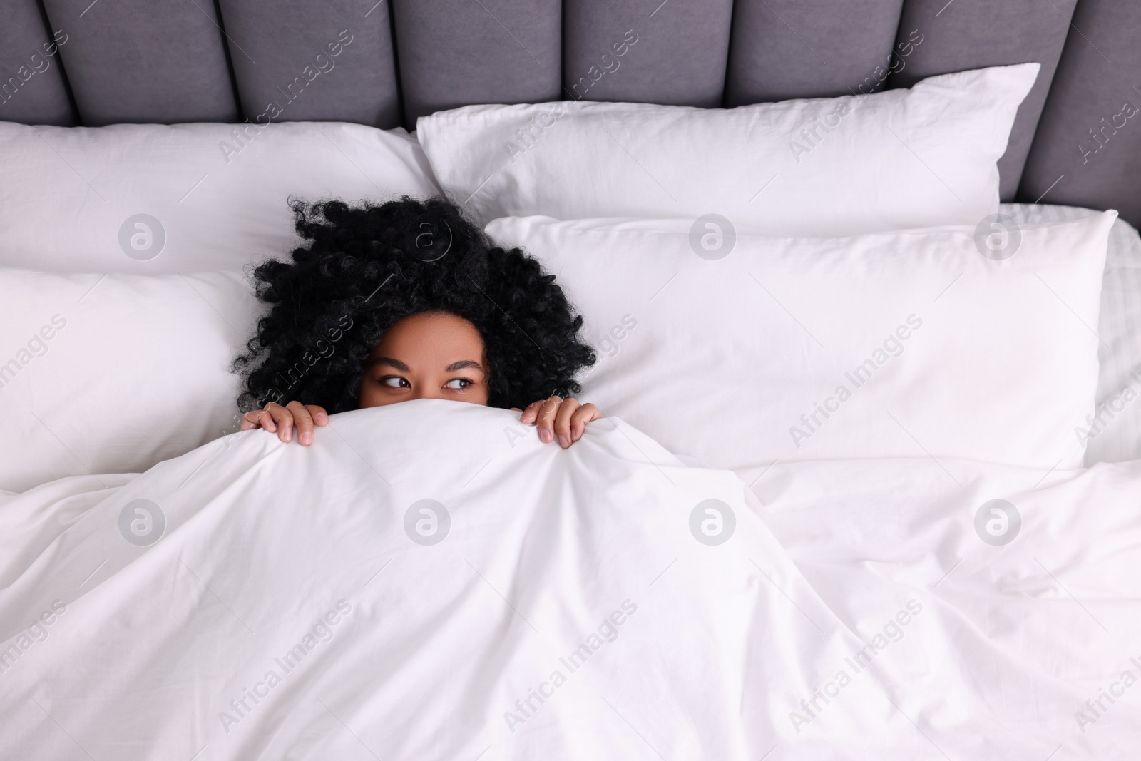 Photo of Young woman lying in soft bed at home, above view