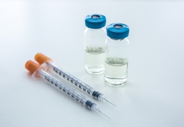 Photo of Vials with medicine and syringes on light background. Vaccination concept