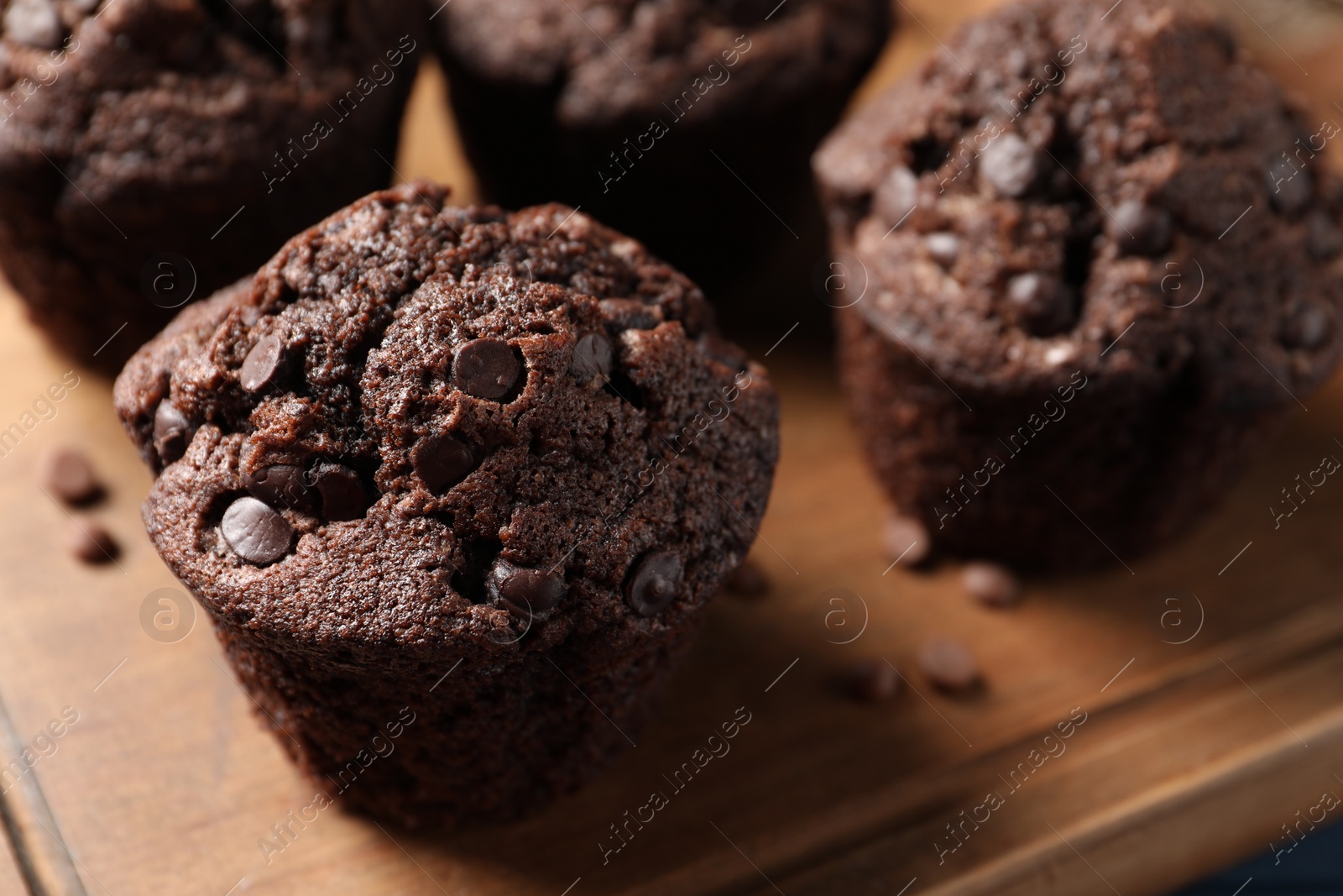 Photo of Delicious chocolate muffins on wooden board, closeup