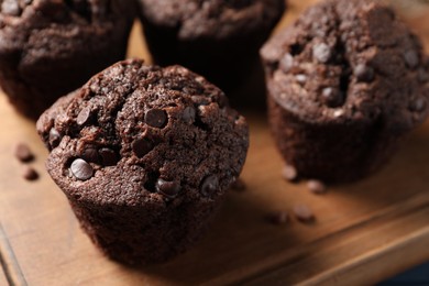 Photo of Delicious chocolate muffins on wooden board, closeup