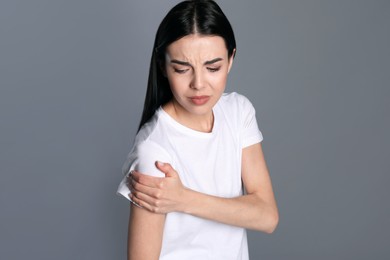 Photo of Woman suffering from shoulder pain on grey background