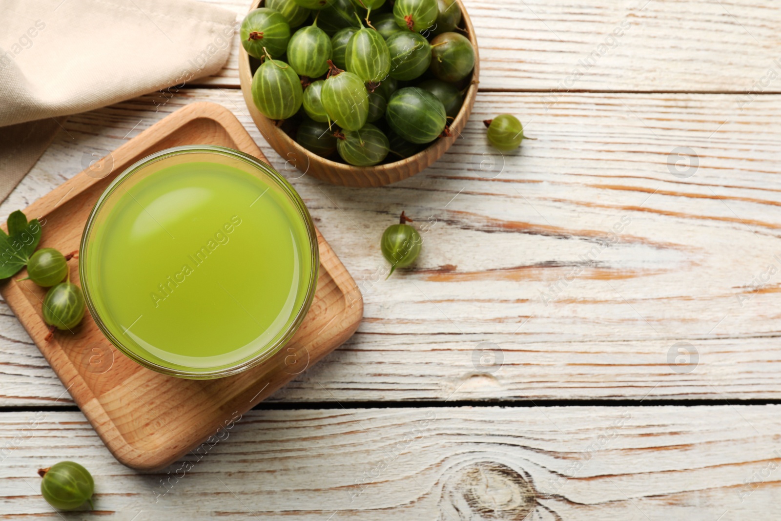 Photo of Tasty gooseberry juice and fresh berries on white wooden table, flat lay. Space for text