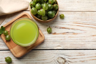 Photo of Tasty gooseberry juice and fresh berries on white wooden table, flat lay. Space for text