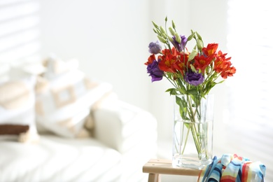 Vase with beautiful flowers on wooden table in room, space for text