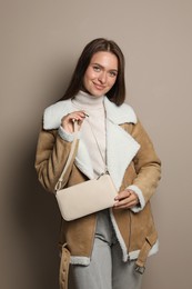 Photo of Fashionable young woman with stylish bag on beige background