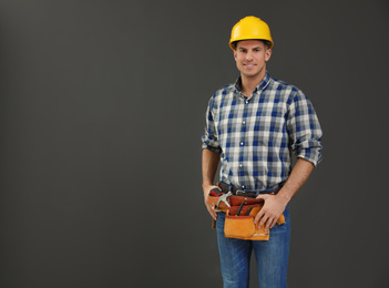 Handsome carpenter with tool belt on dark background. Space for text