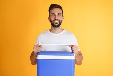 Photo of Happy man with cool box on yellow background