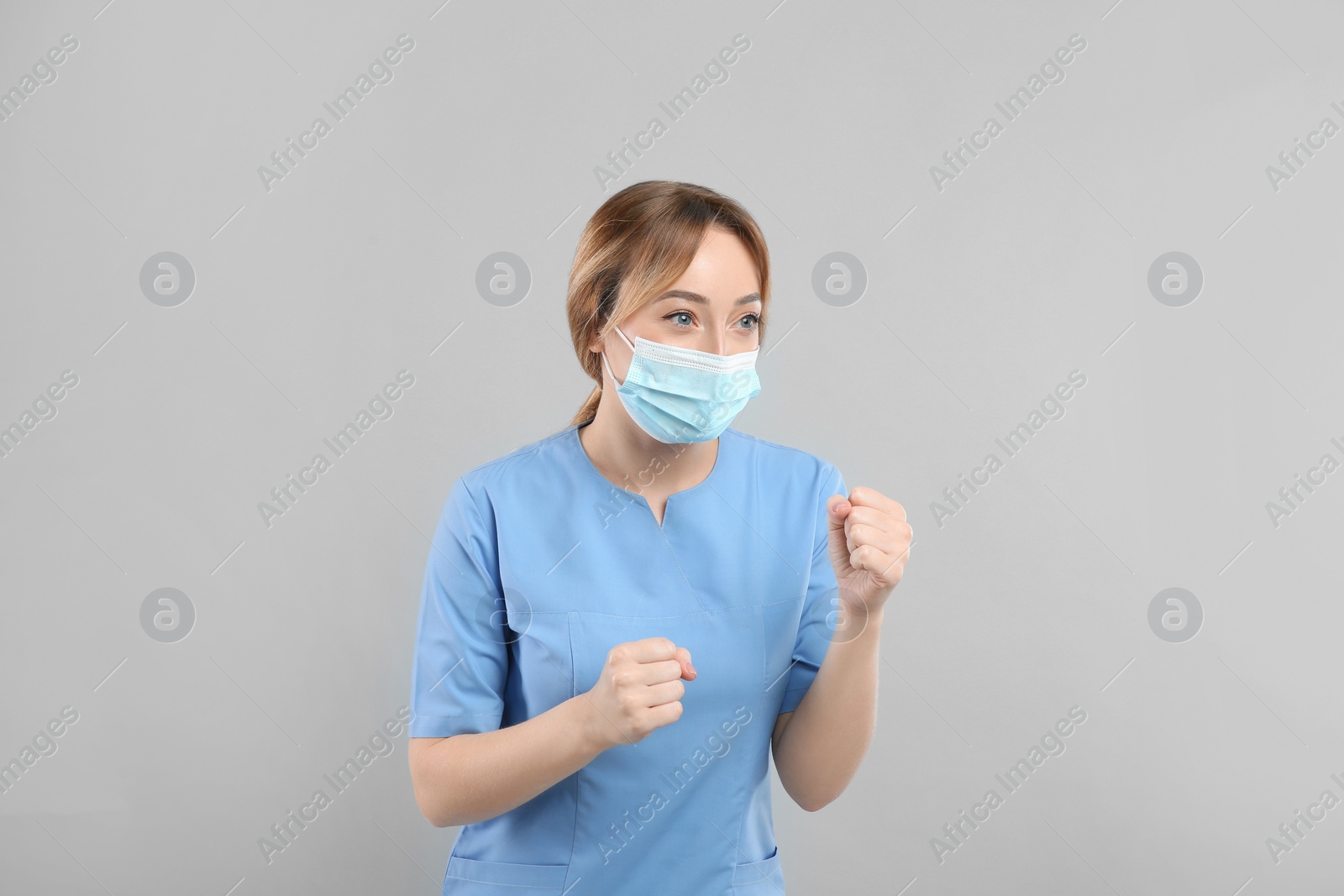 Photo of Doctor with protective mask in fighting pose on light grey background. Strong immunity concept