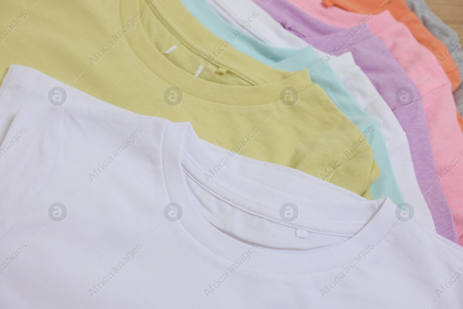 Photo of Many stacked clothes on wooden table, closeup