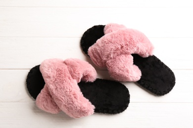 Pair of soft slippers on white wooden background, flat lay