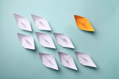 Photo of Yellow paper boat among others on light background, flat lay. Uniqueness concept