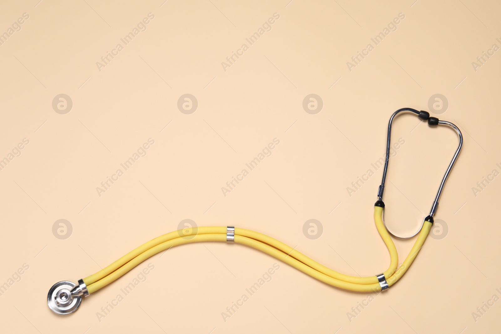 Photo of Stethoscope on beige background, top view. Space for text