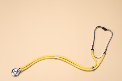 Photo of Stethoscope on beige background, top view. Space for text