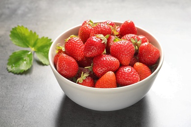 Photo of Bowl with ripe strawberries on grey background