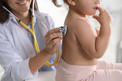 Pediatrician examining baby with stethoscope in clinic, closeup