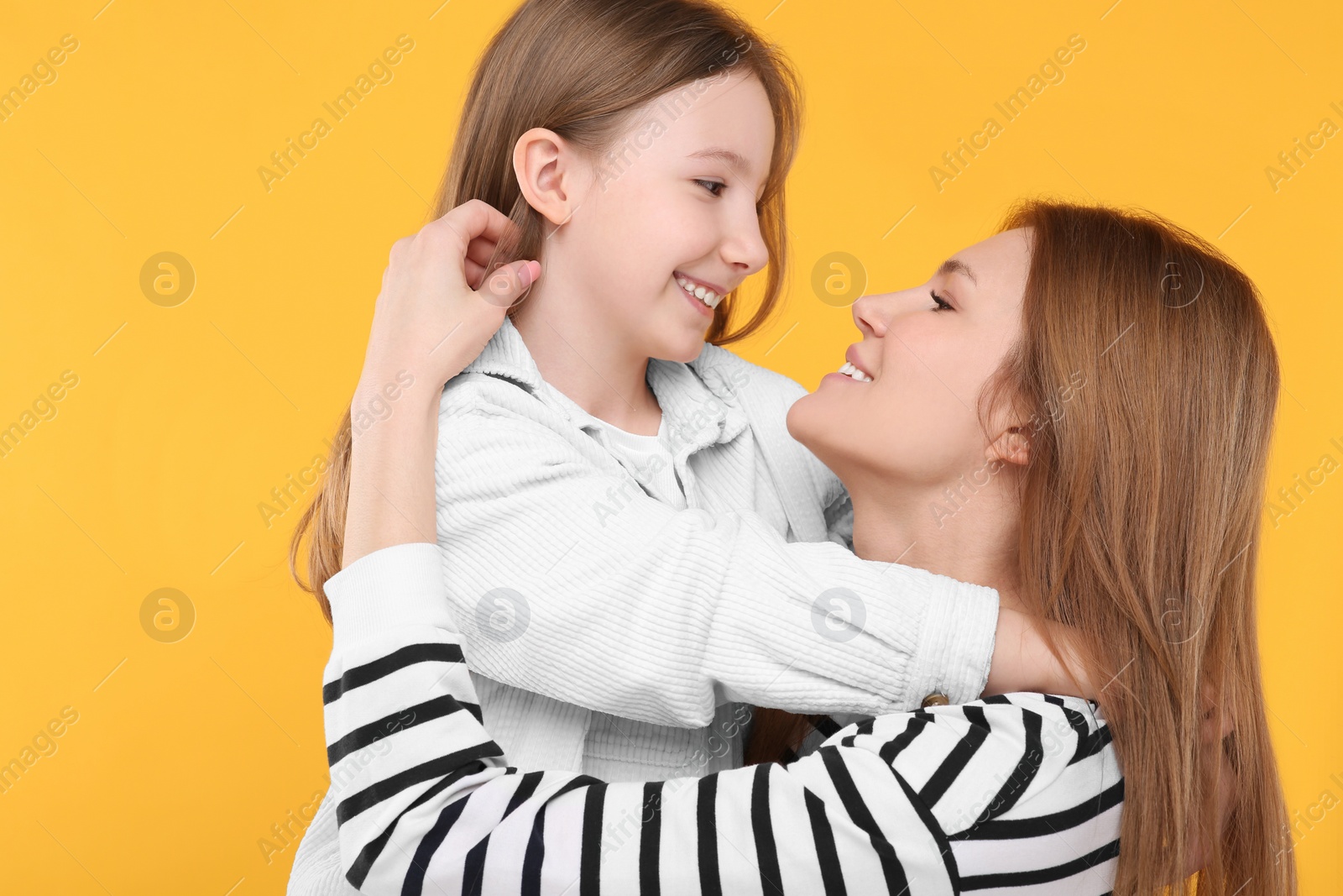 Photo of Portrait of happy mother and her cute daughter on orange background