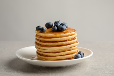 Photo of Plate with pancakes and berries on grey background