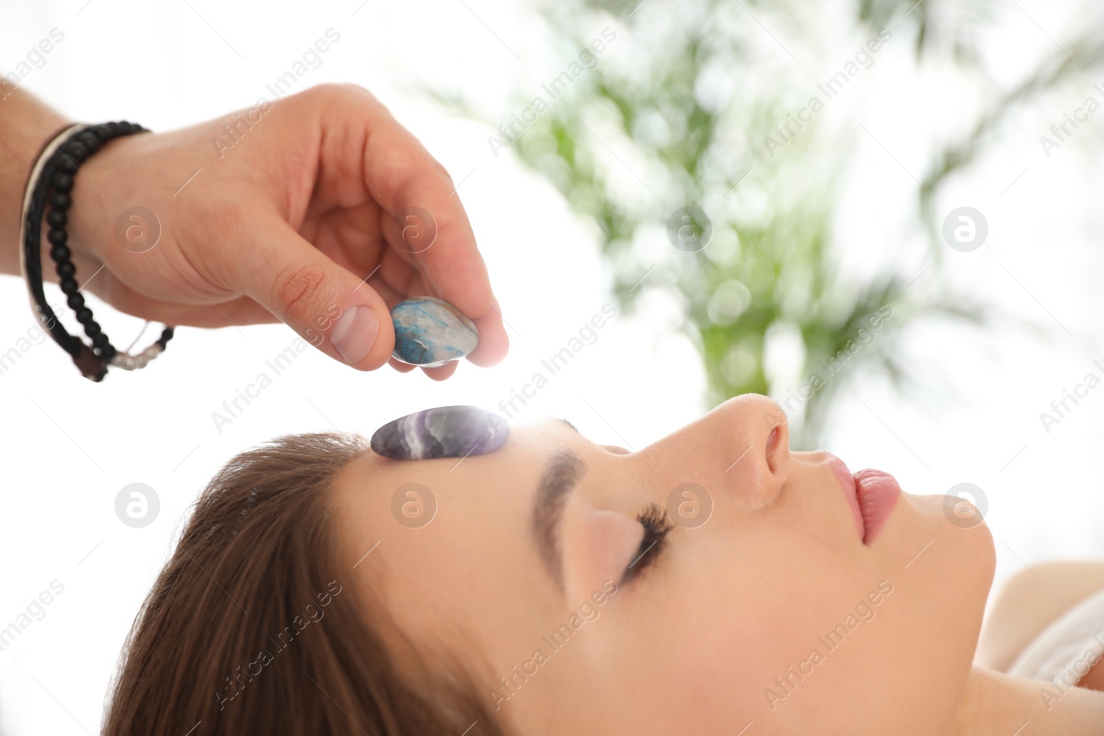 Photo of Young woman during crystal healing session in therapy room