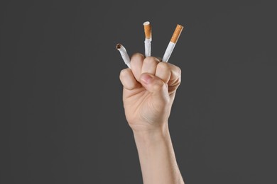 Photo of Stop smoking concept. Woman crushing cigarettes on gray background, closeup with space for text