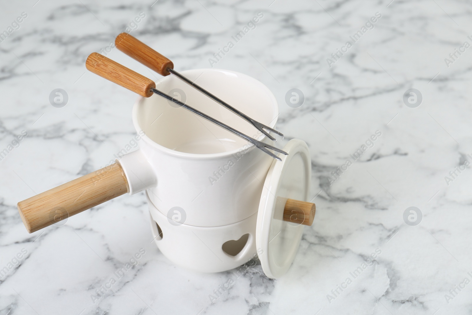 Photo of Fondue set on white marble table. Kitchen equipment