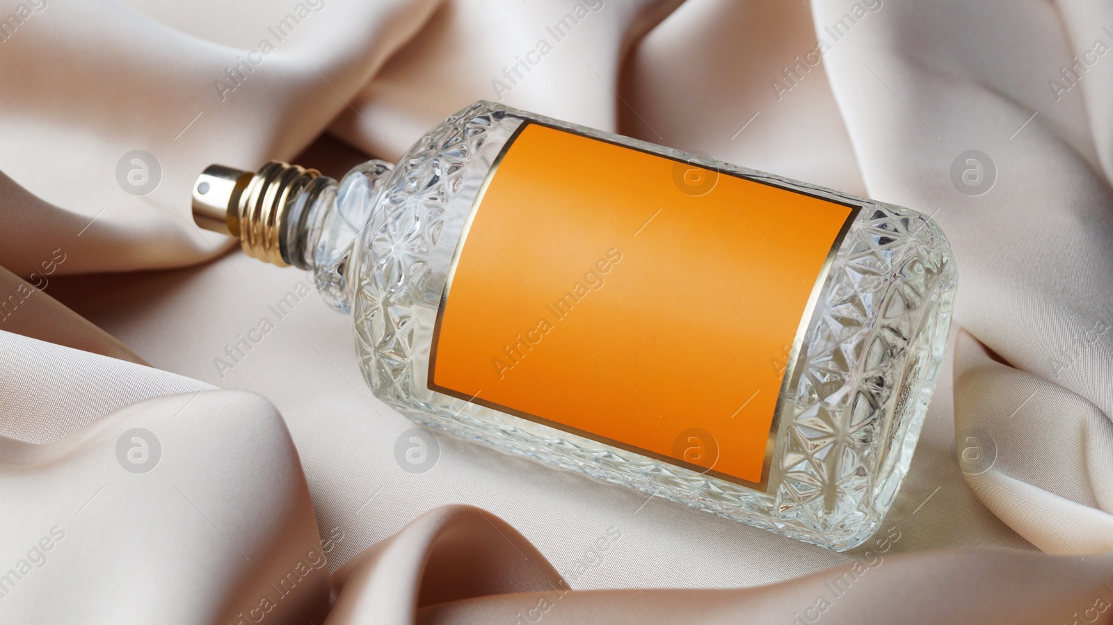 Photo of Luxury bottle of perfume on beige silk