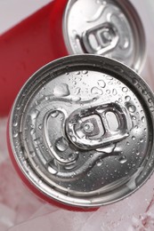 Energy drinks in wet cans on ice cubes, closeup