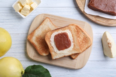 Photo of Toasts with delicious quince paste on white wooden table, flat lay