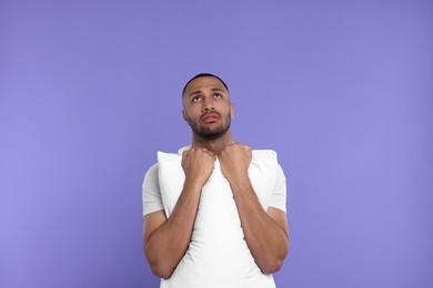 Photo of Tired man with pillow on violet background. Insomnia problem