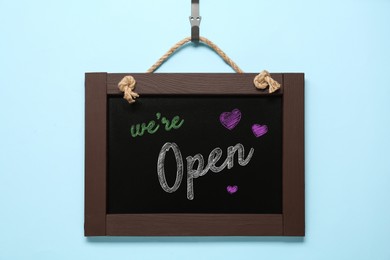 Image of Small chalk board with phrase We're Open on light blue background