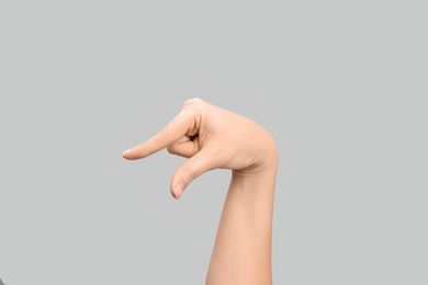 Photo of Woman showing Q letter on grey background, closeup. Sign language