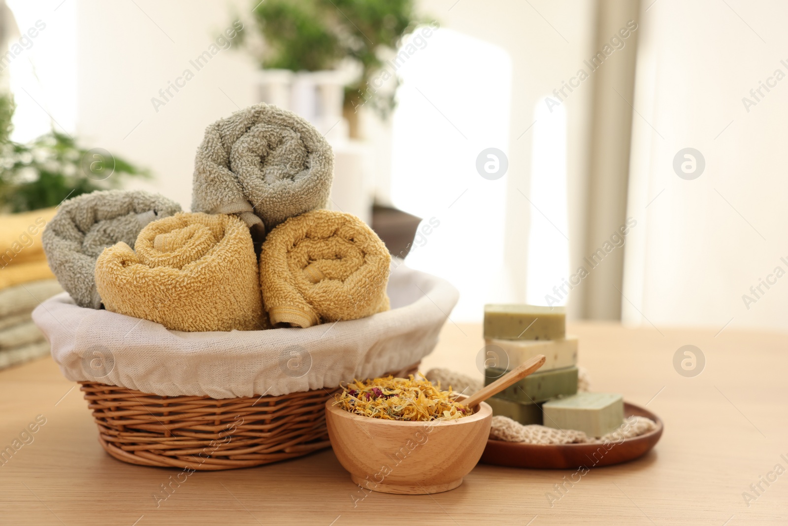 Photo of Dry flowers, soap bars and towels on wooden table indoors, space for text. Spa time