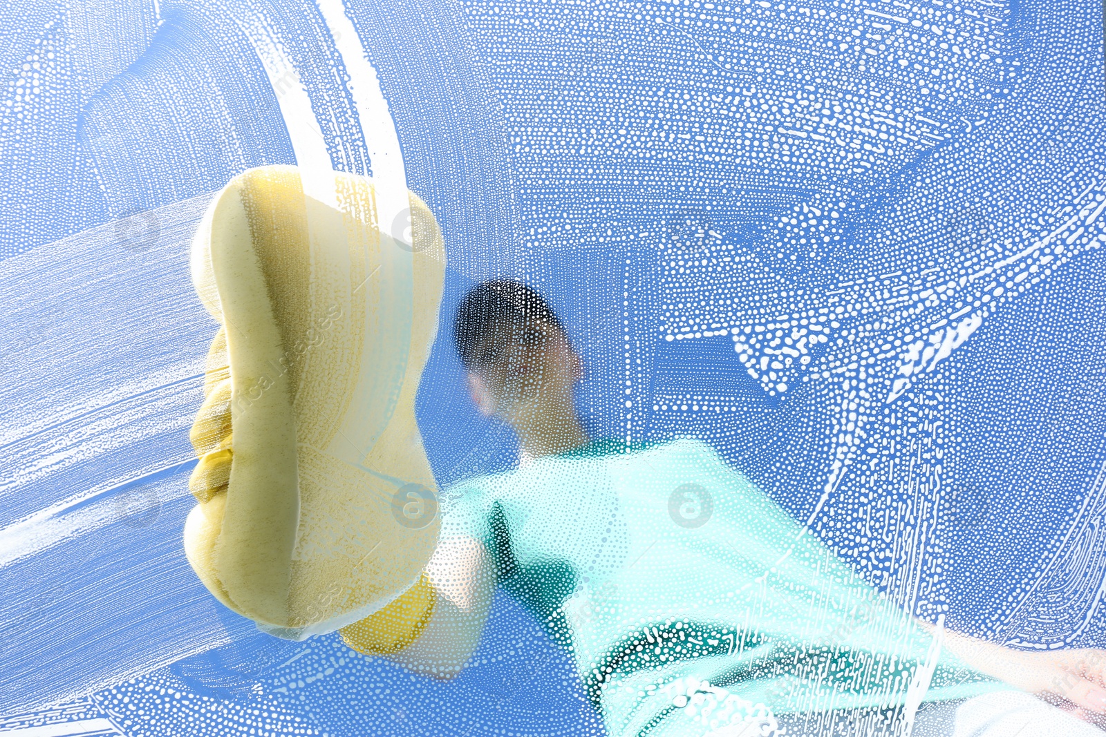 Photo of Woman cleaning glass with sponge on sunny day