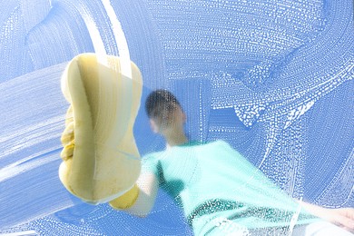 Photo of Woman cleaning glass with sponge on sunny day