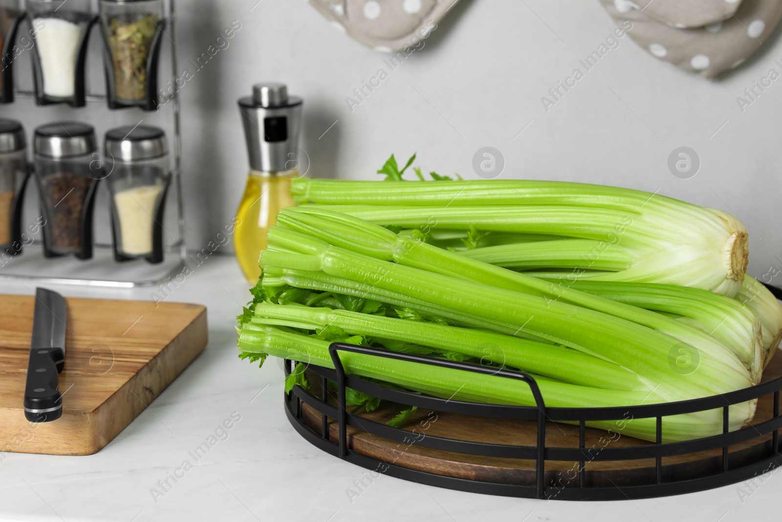 Photo of Fresh ripe green celery on white table in kitchen