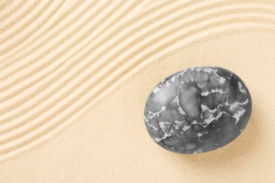 Photo of Zen concept. Stone and pattern on beige sand, top view. Space for text