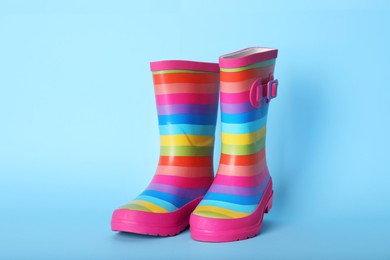 Photo of Pair of striped rubber boots on light blue background