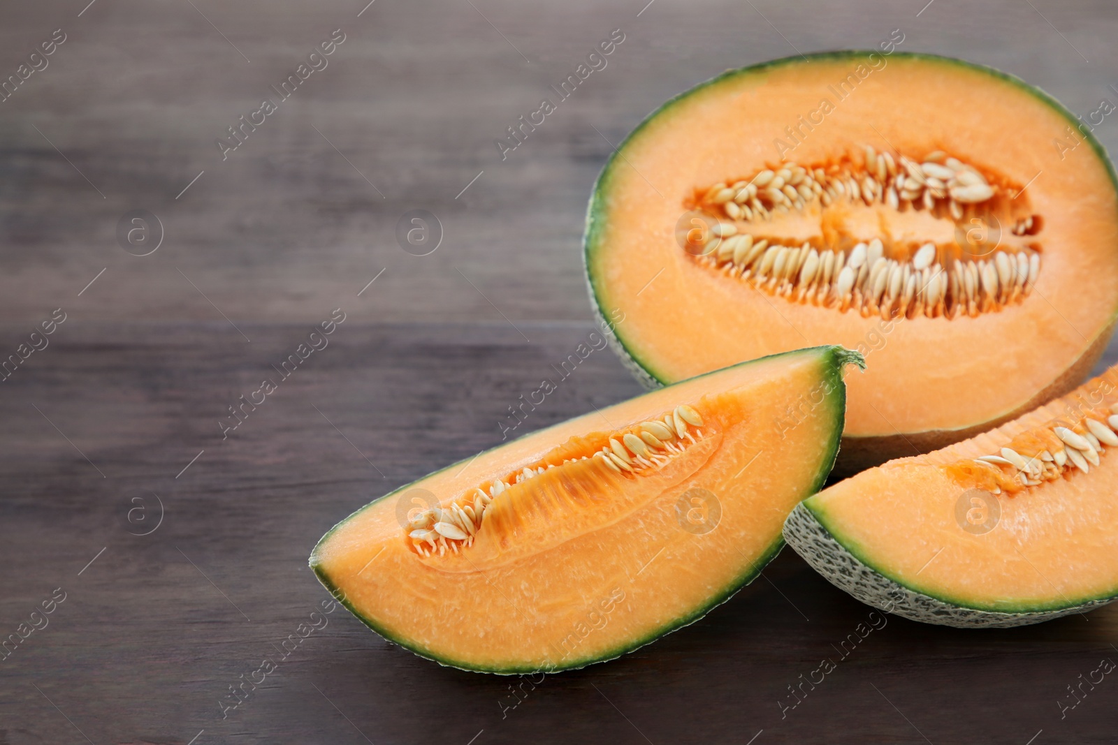 Photo of Tasty orange ripe melons on wooden table. Space for text
