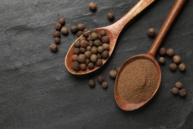 Ground and whole allspice berries (Jamaica pepper) on black table, top view. Space for text