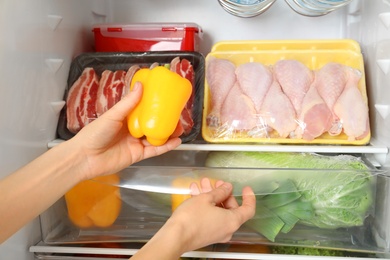 Woman taking bell pepper from refrigerator, closeup