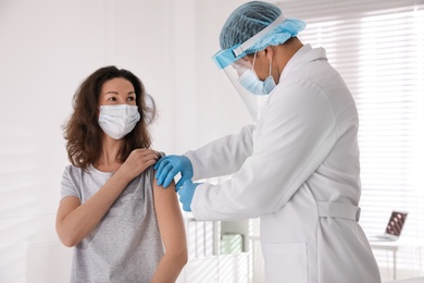 Photo of Doctor vaccinating mature woman against Covid-19 in clinic