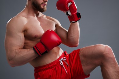 Man in boxing gloves fighting on grey background, closeup