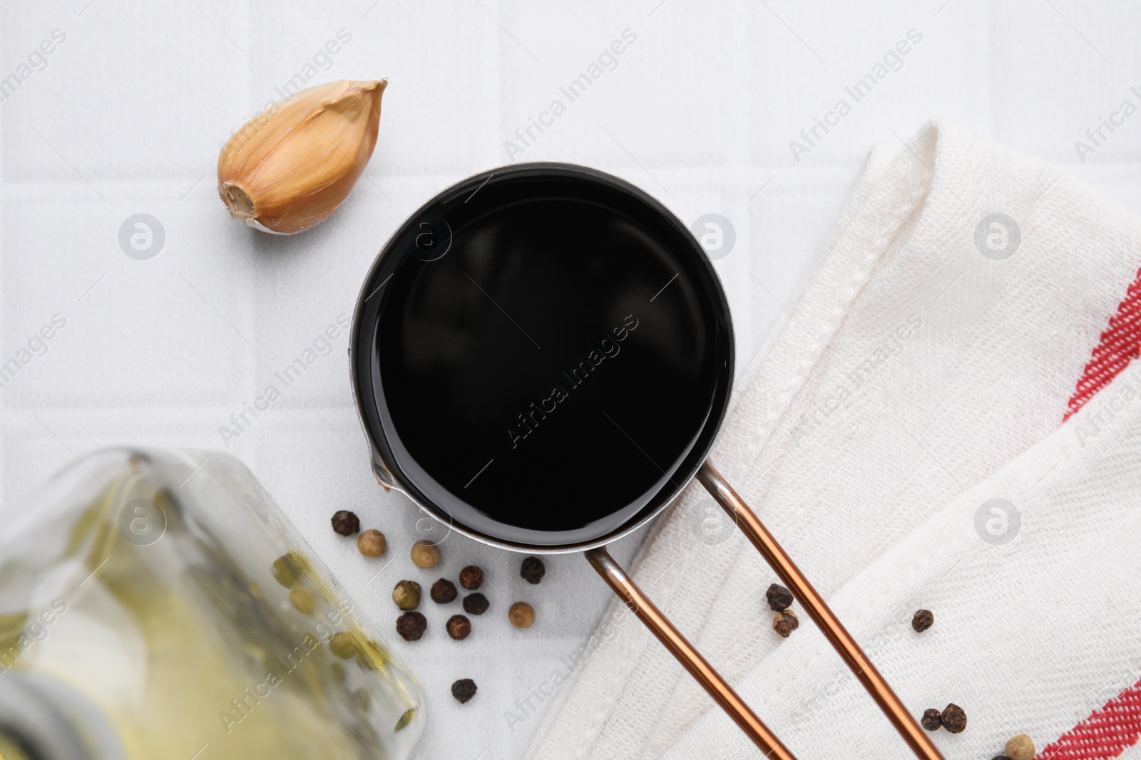 Photo of Metal small saucepan with balsamic vinegar and ingredients on white tiled table, flat lay