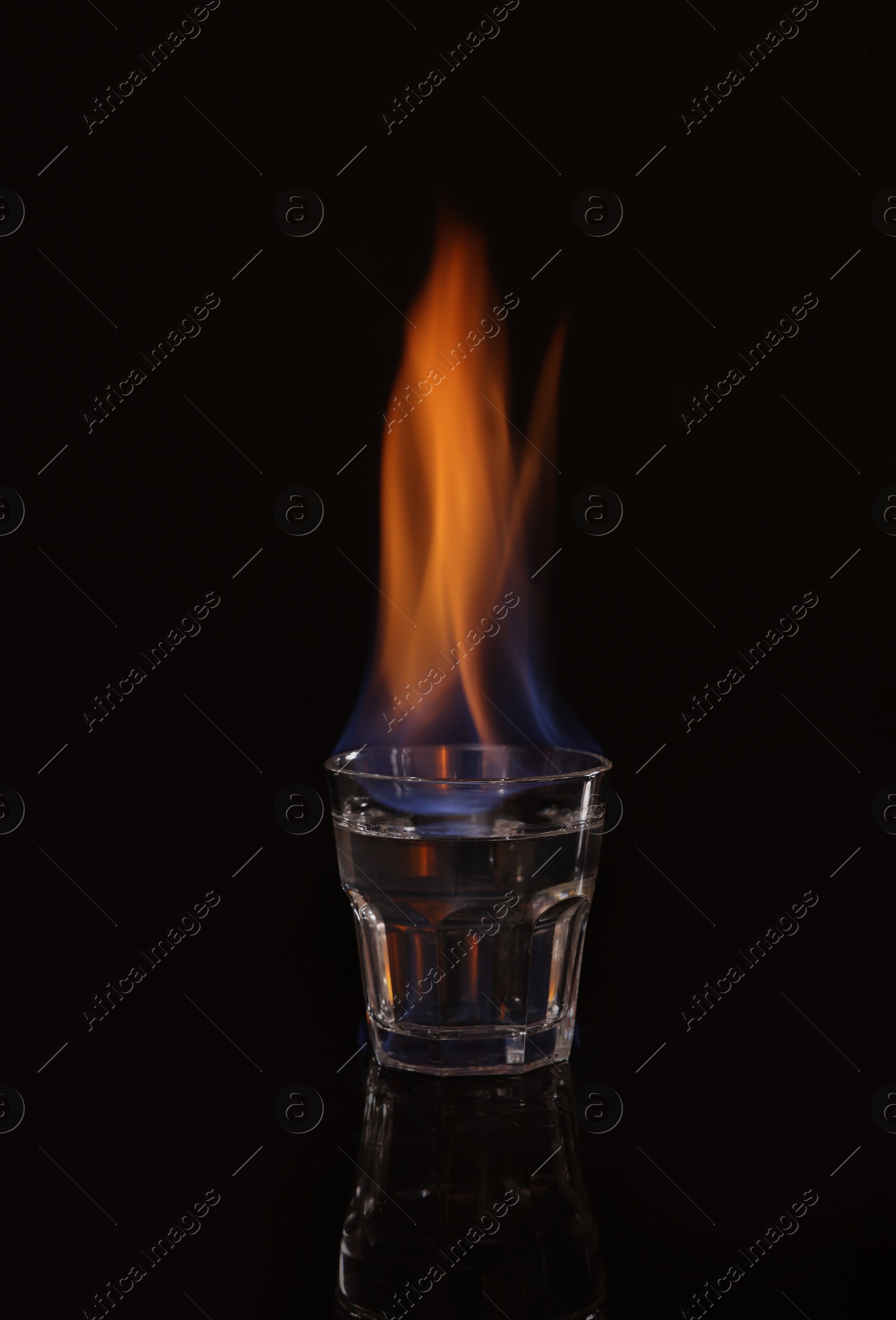 Photo of Flaming vodka in shot glass on black background