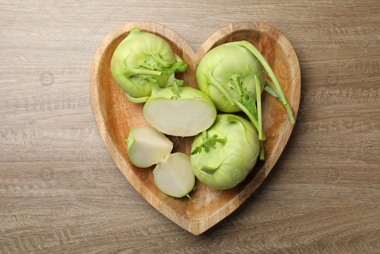 Photo of Whole and cut kohlrabi plants on wooden table, top view