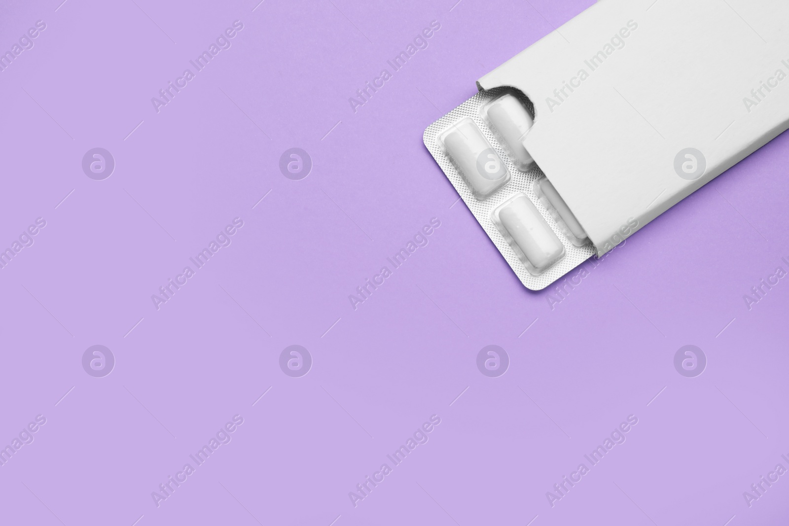 Photo of Blister with chewing gums on violet background, top view. Space for text