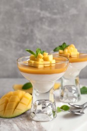Photo of Delicious panna cotta with mango coulis served on light grey table