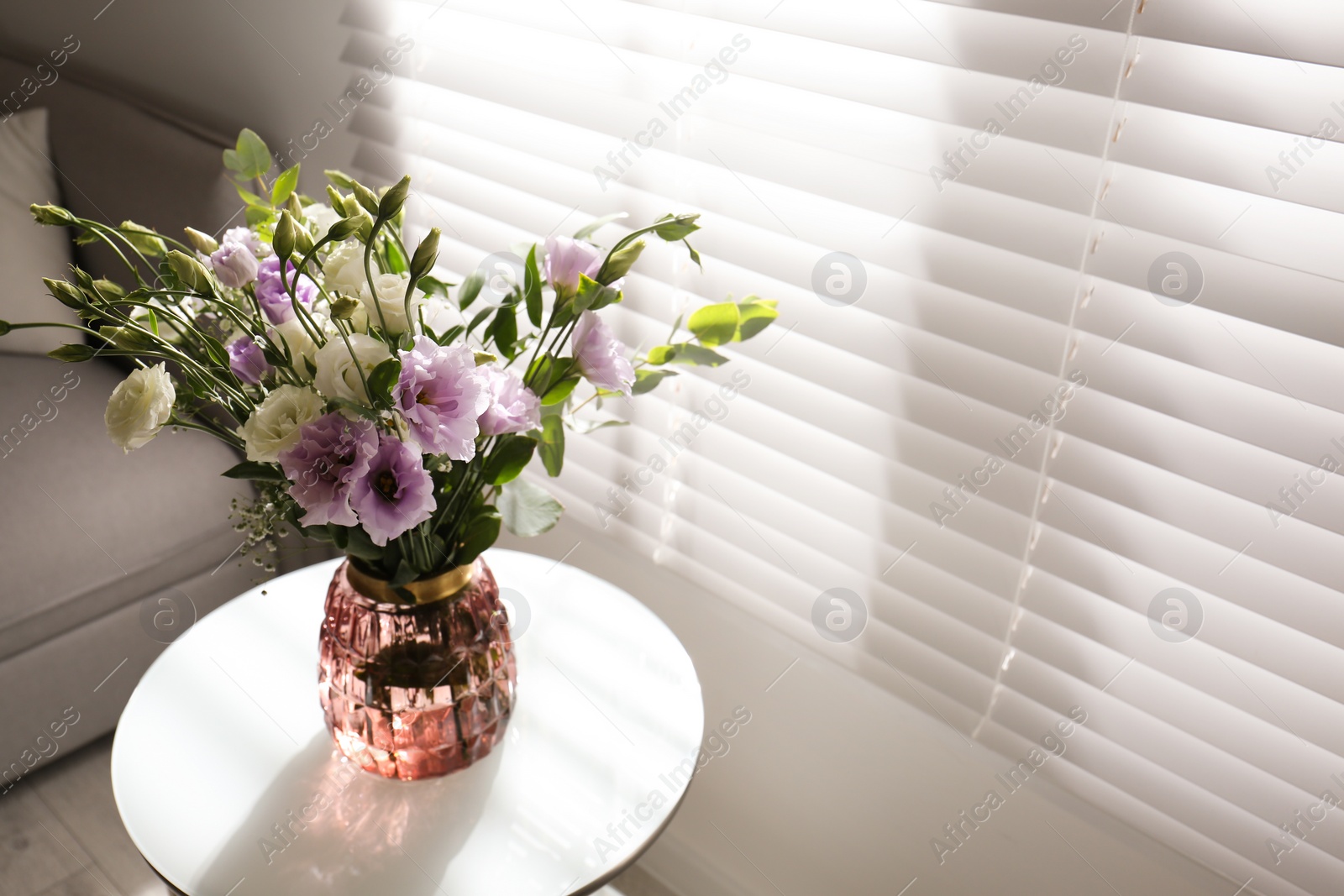 Photo of Bouquet of beautiful Eustoma flowers on table in room. Space for text